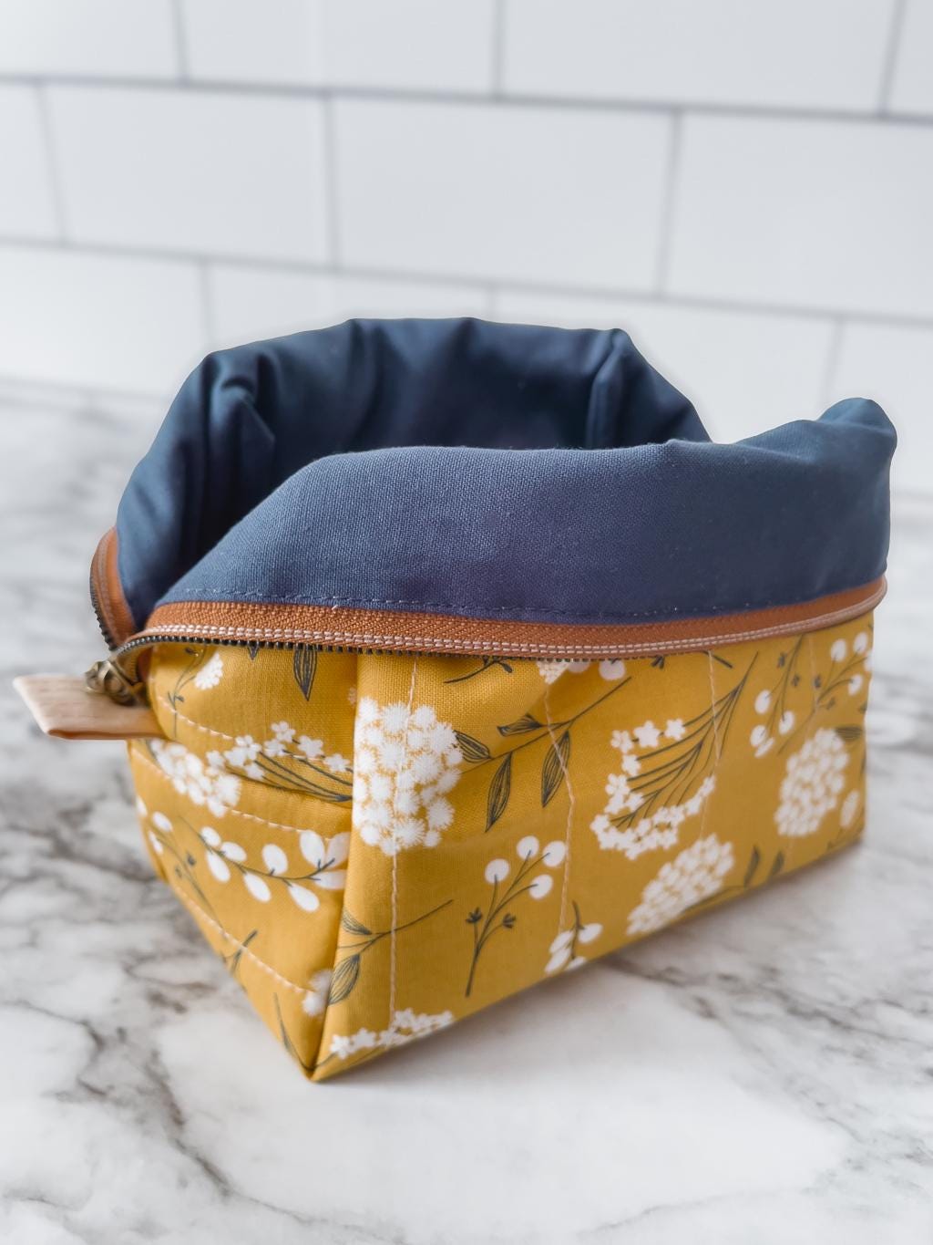 Two fabric bags, one navy and one with floral pattern, on a marble surface.
