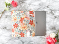 Floral-patterned case on a tablet with flowers on a marble background