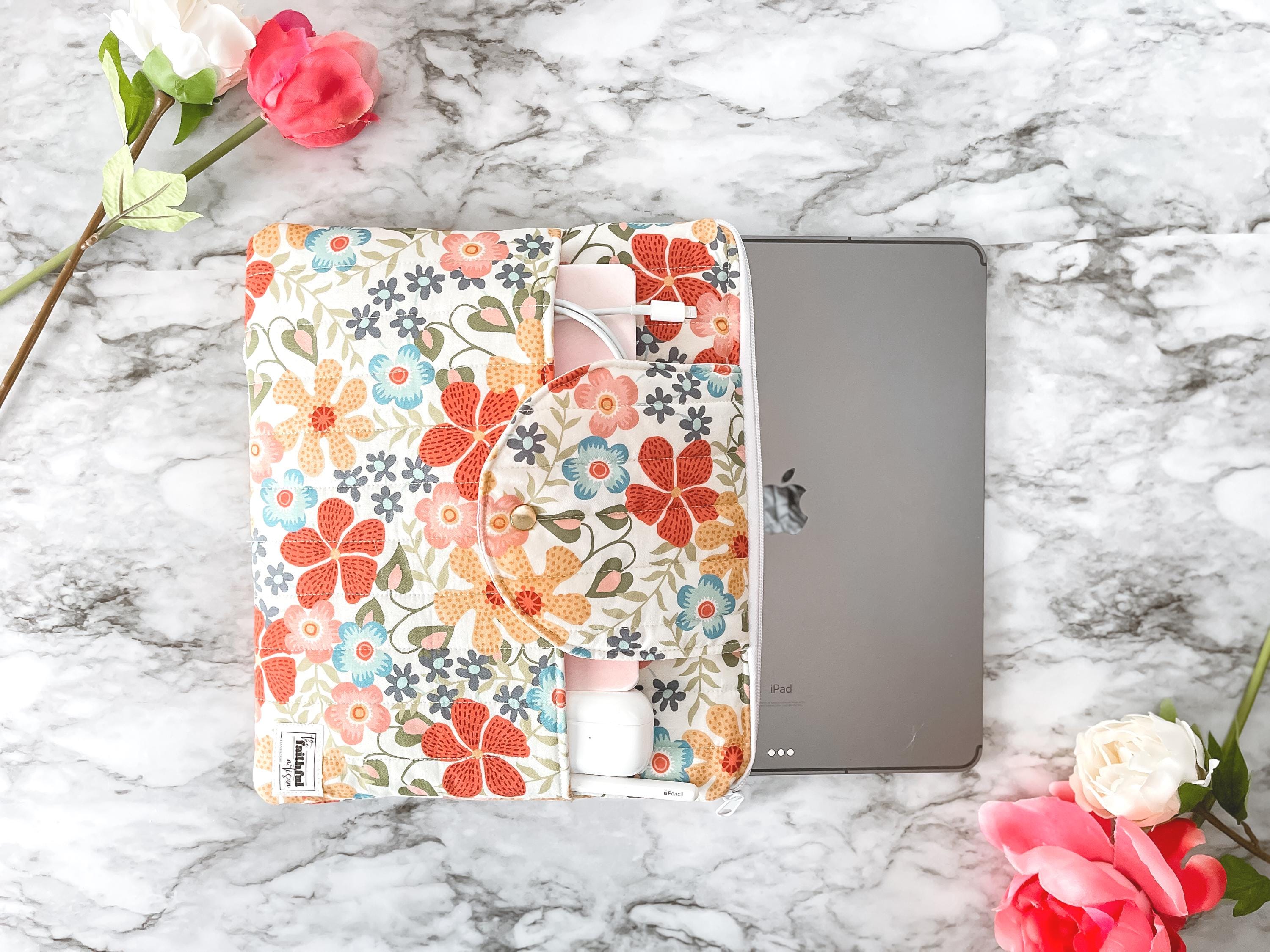 Floral-patterned case on a tablet with flowers on a marble background