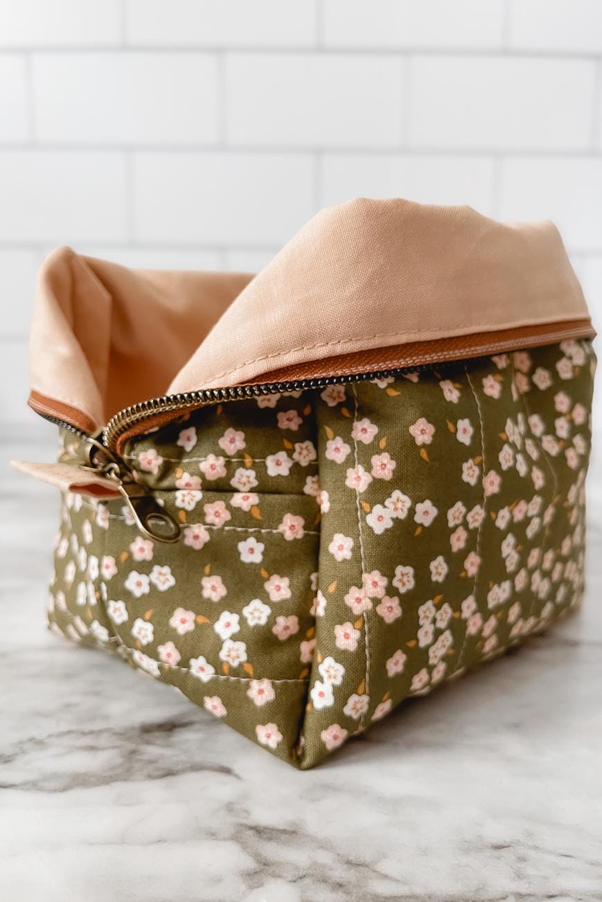Fabric basket with floral pattern and beige top on a marble surface