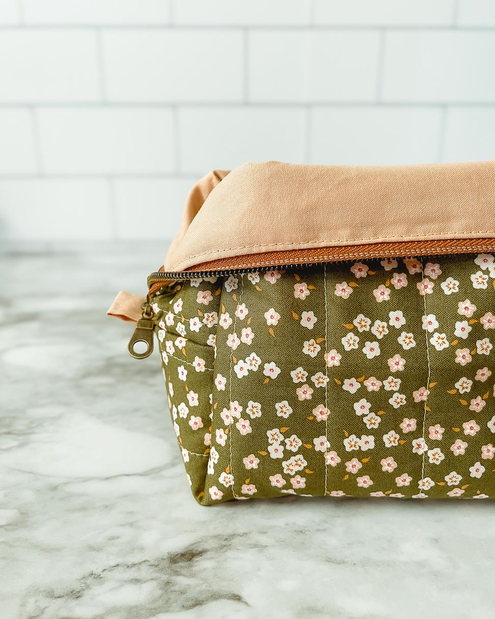 Two pouches, one with a floral pattern and the other beige, on a marble surface.