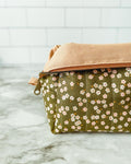 Two pouches, one with a floral pattern and the other beige, on a marble surface.