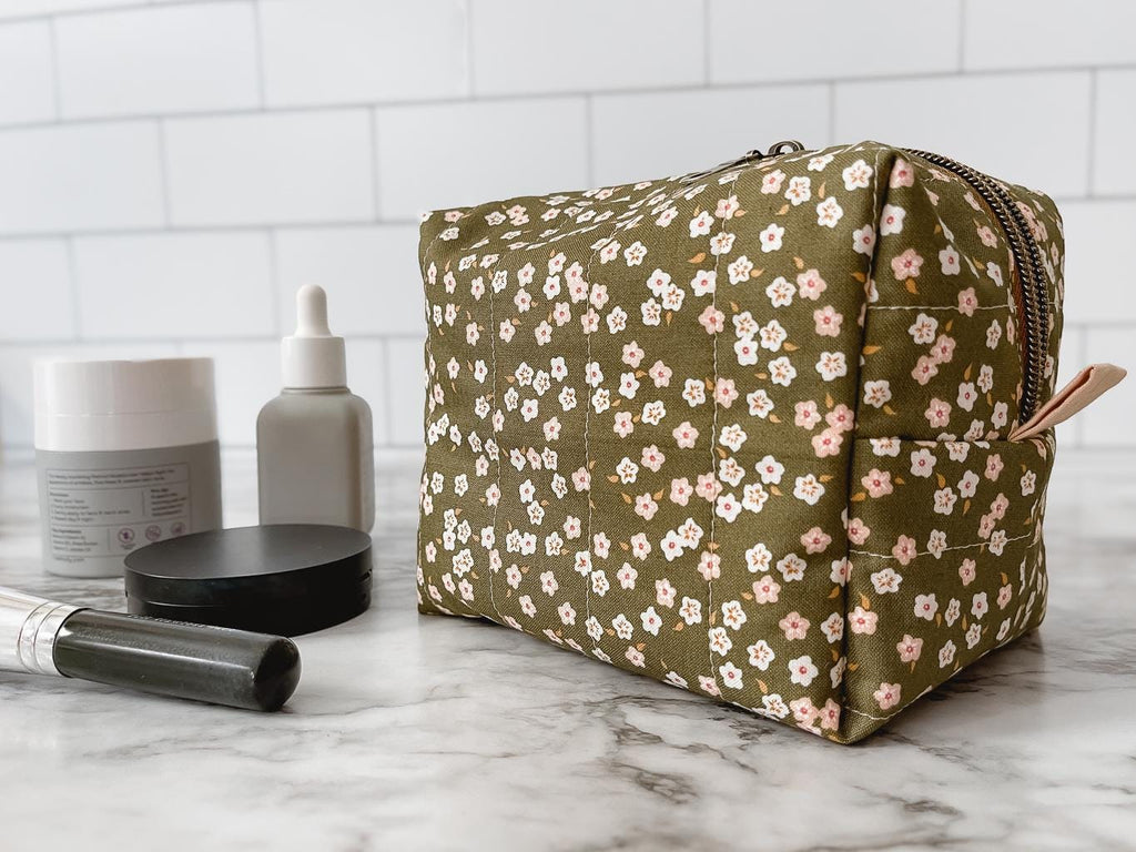 Floral-patterned makeup bag on a marble surface with skincare products.