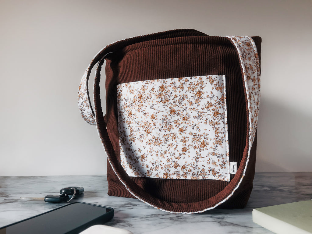 Brown corduroy with floral front slip pocket mini tote shoulder bag on a marble surface