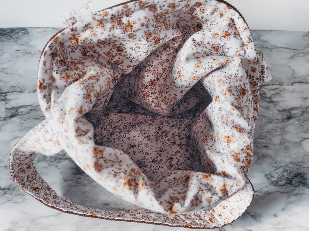 Plush fabric lining with brown floral design mini tote on a marble surface