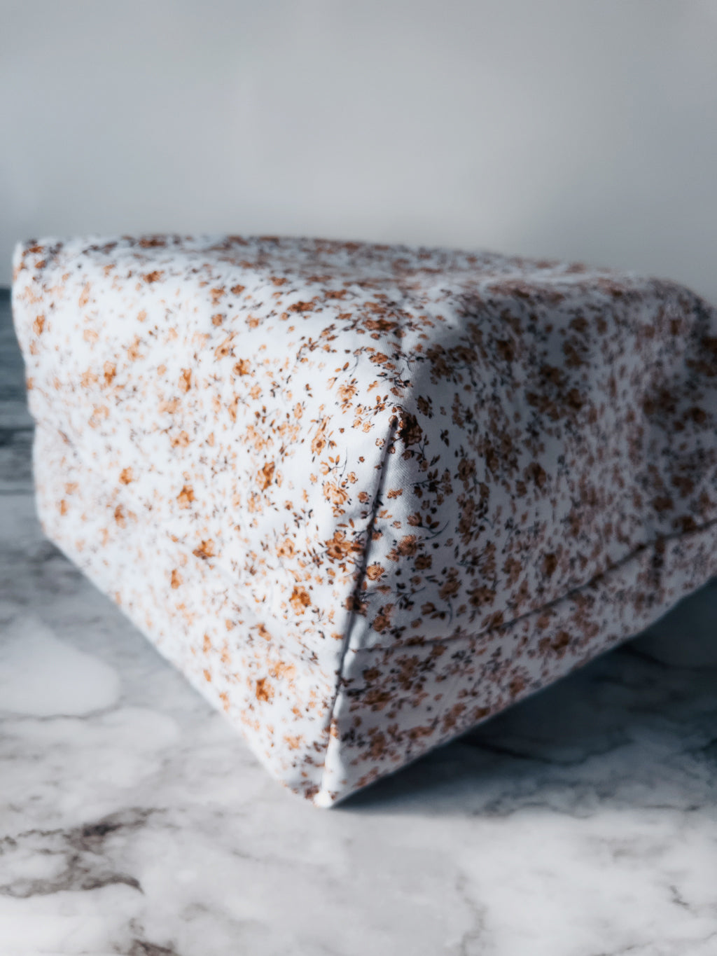 Inside out view of lining boxed corner for mini tote with a floral pattern on a marble surface