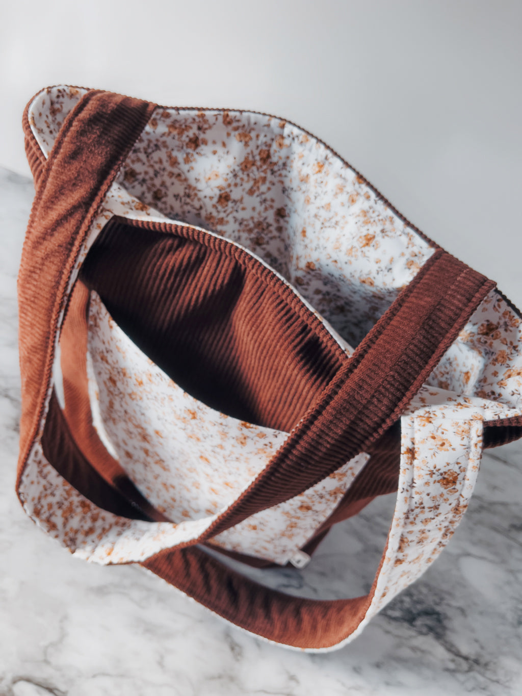 Brown corduroy and floral patterned fabric on a marble surface