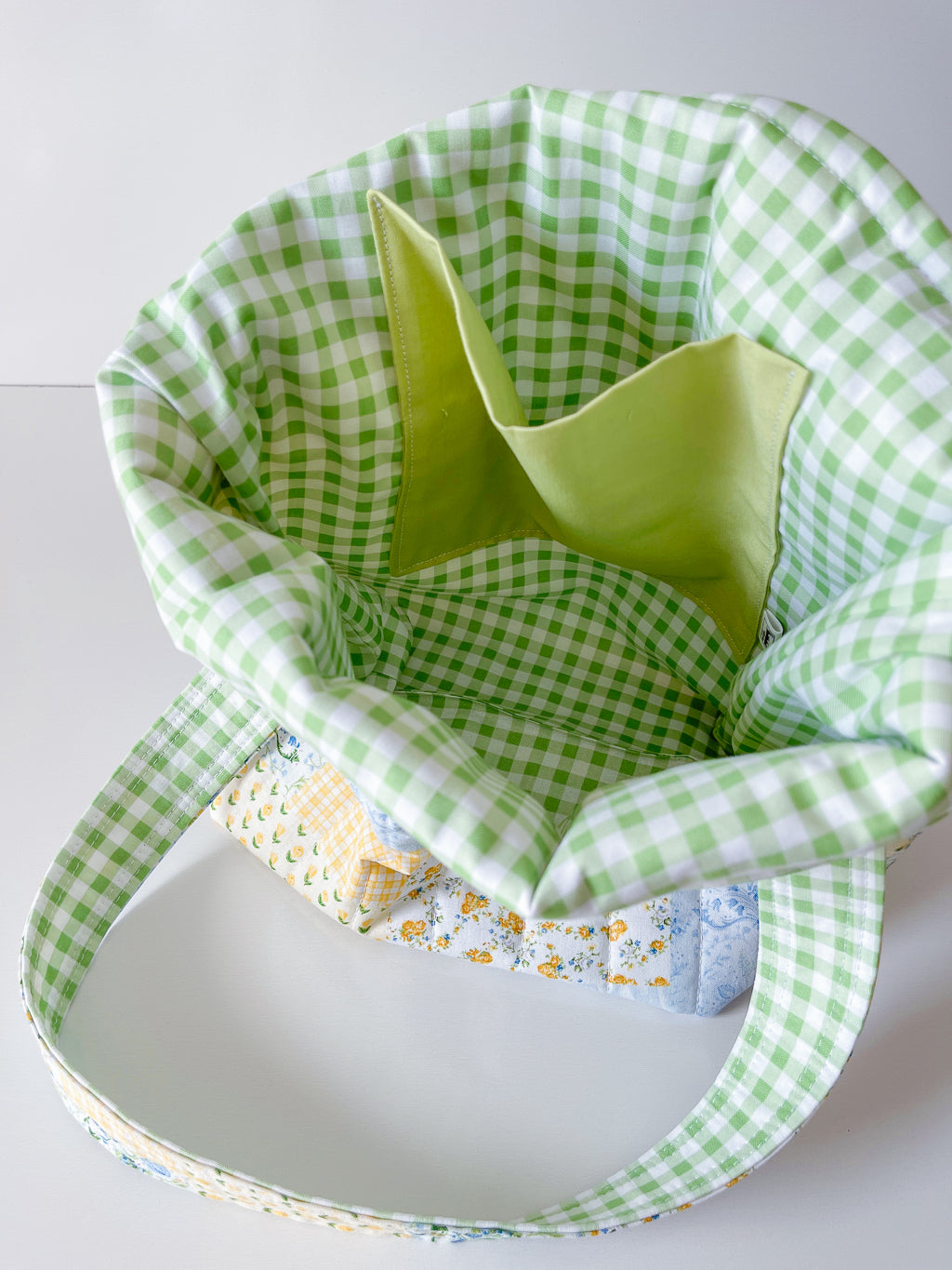 Green gingham fabric basket with a yellow interior on a white background