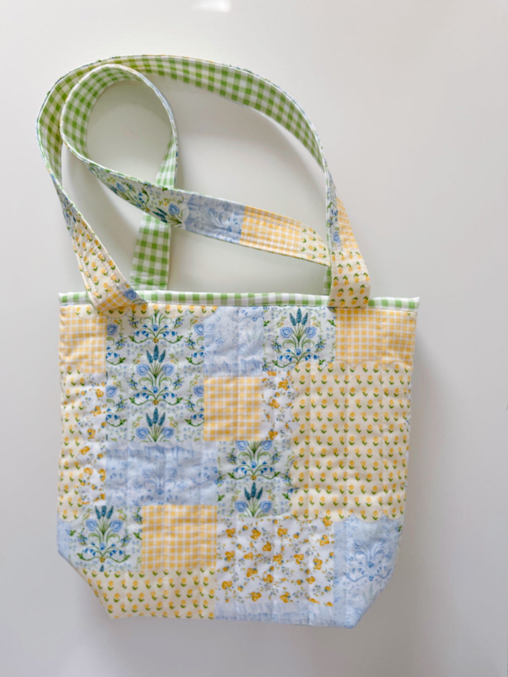 Patchwork tote bag with floral and checkered patterns on a white background