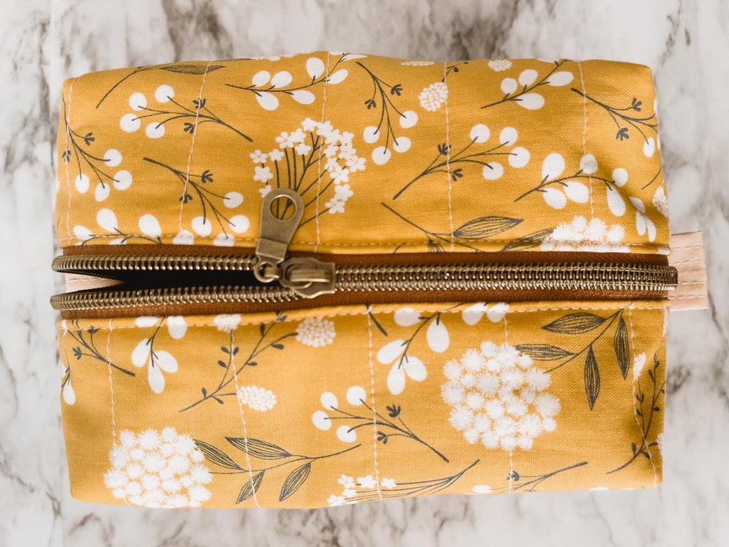 Floral-patterned pouch with a gold zipper on a marble surface