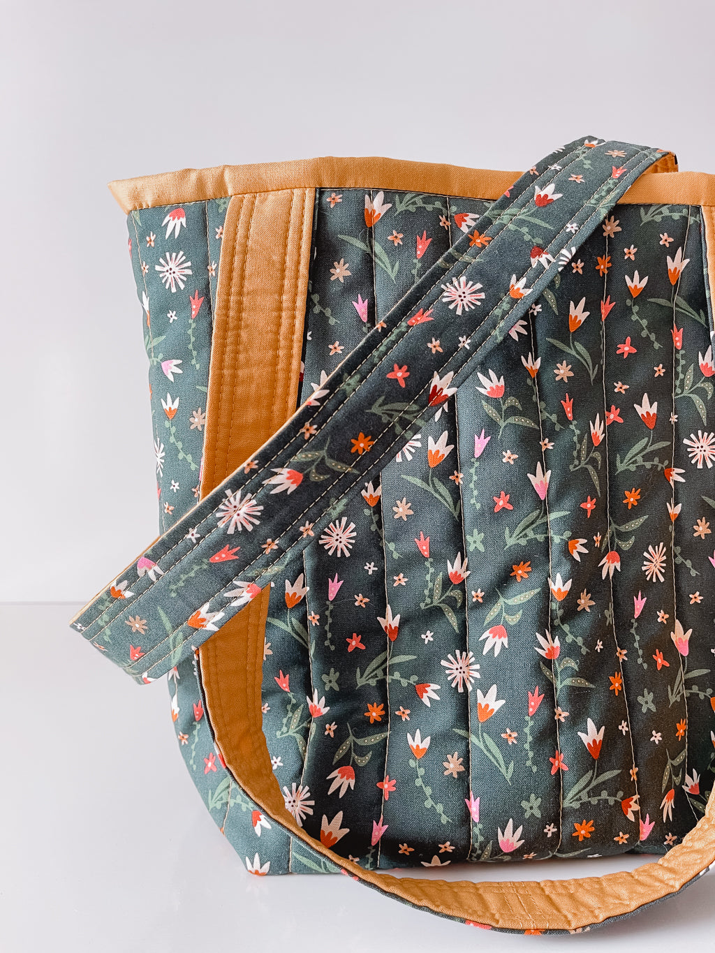 Floral-patterned bag with brown accents on a light gray background