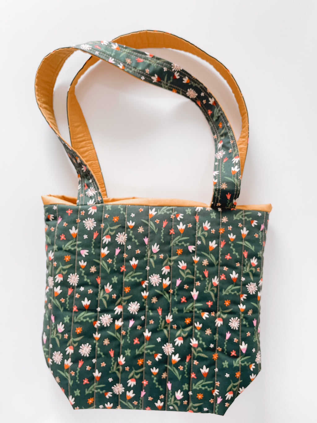 Floral-patterned tote bag with brown handle on a white background