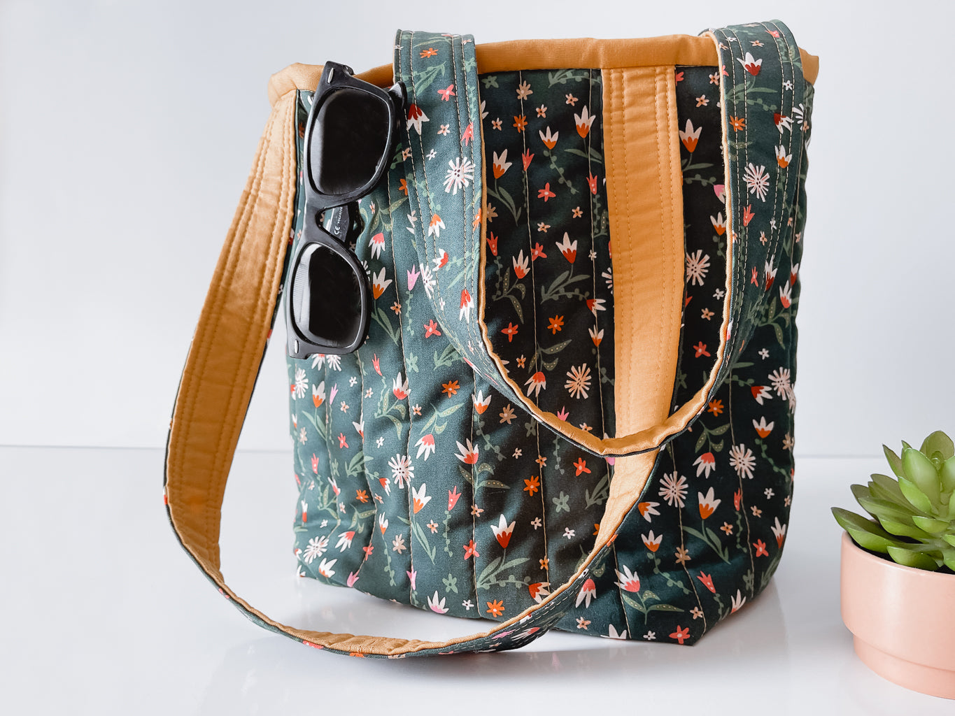 Floral patterned handbag with sunglasses on a white background