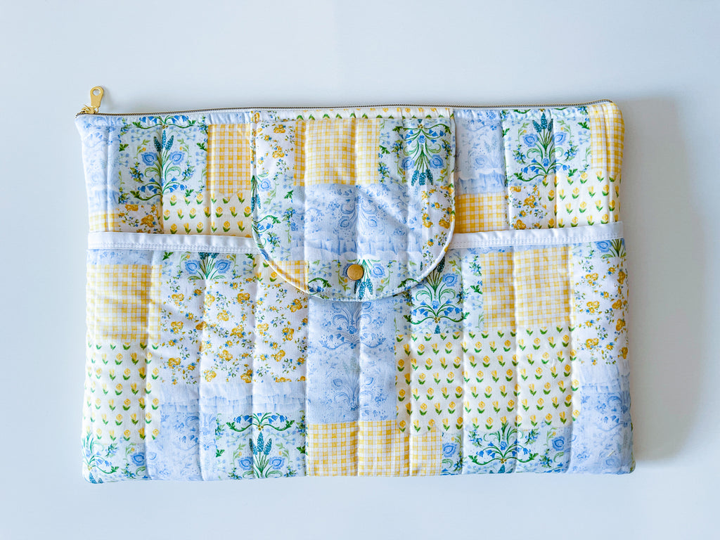 Patchwork print laptop sleeve with floral and checkered patterns on a white background yellow blue green colors
